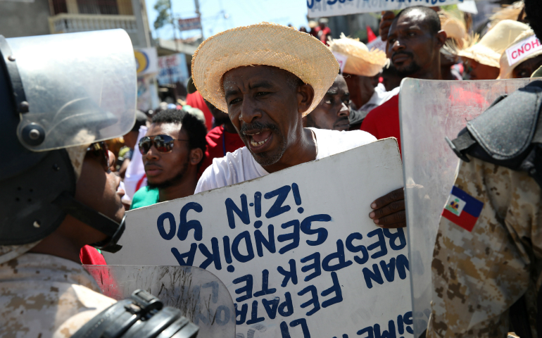 A man argues with a Haitian National Police officer March 1 as a police line blocks a street during a march calling for better labor conditions in Port-au-Prince. (CNS photo/Andres Martinez Casares, Reuters)