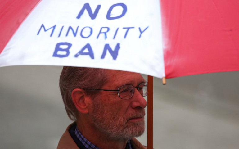 A man holds an umbrella during a protest in Seattle May 15 against President Donald Trump's travel ban. The U.S. Court of Appeals for the 4th Circuit, based in Virginia, issued a 10-3 ruling May 25 to uphold a Maryland federal court's injunction against the temporary ban. (CNS photo/David Ryder, Reuters)