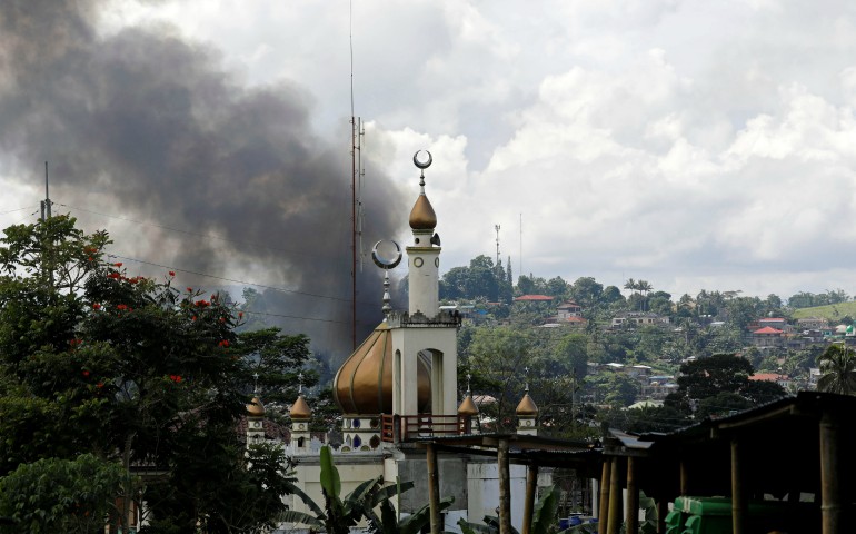 Smoke billows near a mosque in Marawi, Philippines, May 30. Catholic bishops in the southern Philippines supported the declaration of martial law in Mindanao following an attempt by a band of gunmen claiming to be Islamic militants to seize the city. (CNS photo/Erik De Castro, Reuters)