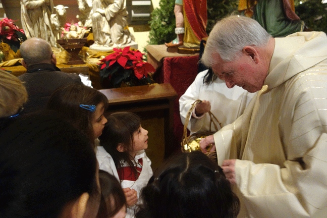 Fr. Michael Ryan, pastor of Seattle's St. James Cathedral, shares candies with children taking part in the Jan. 3 liturgy of the Epiphany of the Lord. (Courtesy of St. James Cathedral)