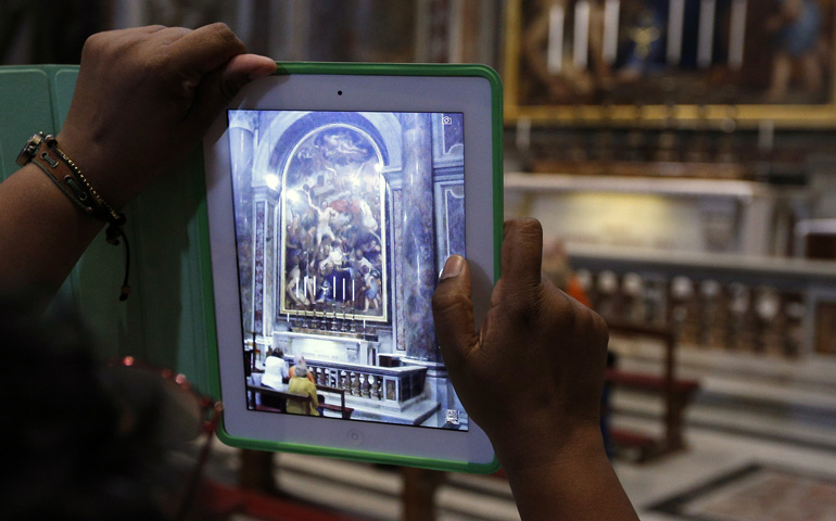 A visitor uses an iPad to take a photo of the tomb of St. John Paul II in September in St. Peter's Basilica at the Vatican. (CNS/Paul Haring)