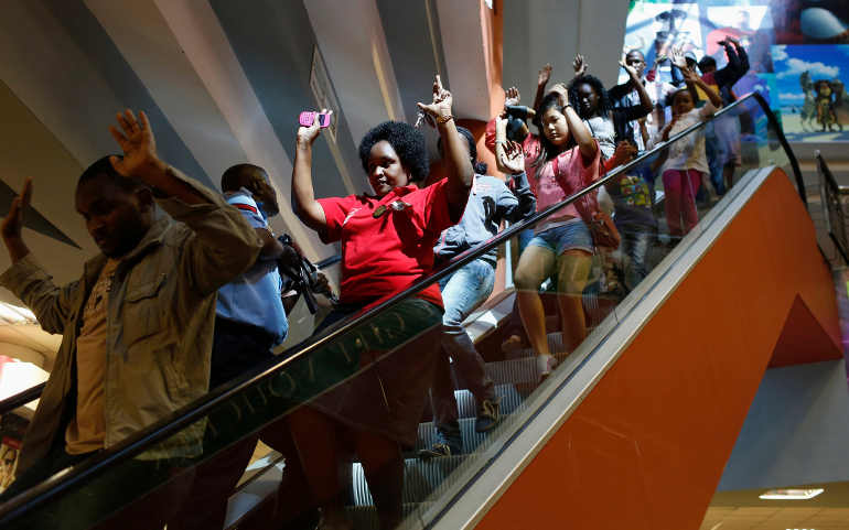 Civilians escape an area at the Westgate mall in Nairobi, Kenya, Sept. 21. Kenya's military said Sept. 23 it had rescued most of the hostages being held captive by al-Qaida-linked militants during a standoff that killed dozens of people and injured at le ast 175. (CNS/Siegfried Modola, Reuters)