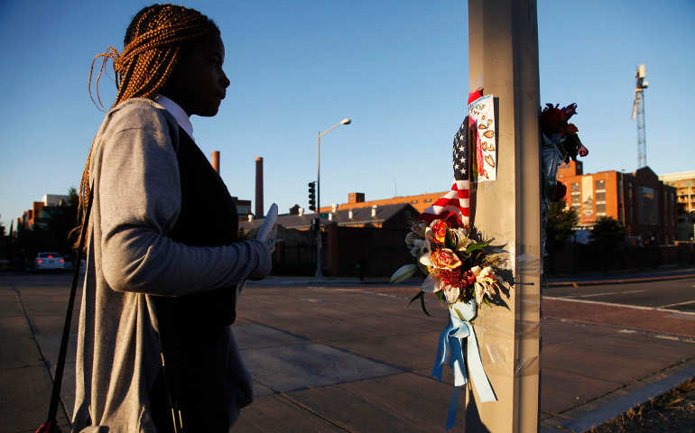 A woman pauses in front of a pole decorated with flowers, flags and a child's drawing Sept. 18 outside the Navy Yard in Washington, two days after a gunman went on a shooting spree. (CNS/Jonathan Ernst, Reuters)