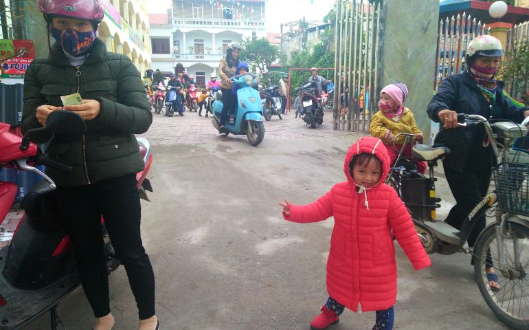Three-year-old Nguyen Thuy Linh (in red) waves goodbye to the Lovers of the Holy Cross who run Anh Duong Nursery School in Yen Bai City before she and her mother, Mary Tran Thi Van Quynh, left, leave for home. (Joachim Pham)