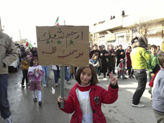 A demonstrator holds a sign reading, "Have mercy on your people, God's mercy on you," during a protest against Syrian President Bashar al-Assad in Ma'arrat al-Numan, near Adlb, Dec. 26. (Newscom/Reuters/Handout)