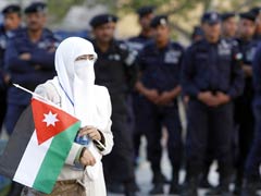A woman holds the Jordanian flag as she walks past a line of police in Amman April 1 during a demonstration calling for reforms. (AFP/Khalil Mazraawi)
