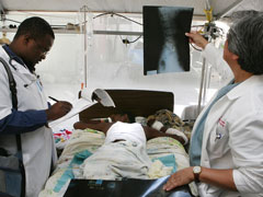 Dr. Edgar A. Gamboa, right, a trauma specialist from Scripps Mercy Hospital in San Diego, works with Haitian Dr. Theony Deshommes at St. Francis de Sales Hospital in Port-au-Prince, Haiti, in January 2010, after the earthquake destroyed most of the center's facilities. (CNS/Bob Roller)