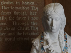 A prayer for the canonization of Blessed Kateri Tekakwitha appears behind a statue of her inside St. Peter's Chapel on the grounds of the shrine dedicated to her. (CNS /Nancy Wiechec)