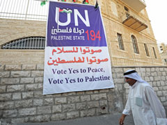 A Palestinian man walks by a banner promoting the Palestinian bid for statehood in the West Bank town of Bethlehem Sept. 18. (CNS/Debbie Hill)