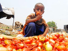 A Pakistani boy eats a discarded tomato as he sits amid trash in a slum in Lahore Aug. 15. Nearly 120 million of the total population here are forced to spend 50 to 70 percent of their incomes on food. (Xinhua Photo/Jamil Ahmed)
