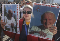 A woman in St. Peter's Square holds photos with the words, "Blessed Pope John Paul II," written in Italian as Pope Benedict XVI leads the Angelus prayer at the Vatican Jan. 16. (CNS/Paul Haring)