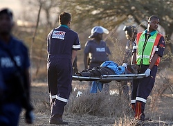 Paramedics carry an injured man after protesting miners were shot outside a South African mine Thursday in Marikana. (CNS/Reuters/Siphiwe Sibeko)