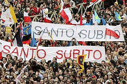 Mourners hold banners that read "sainthood now" during the funeral Mass for Pope John Paul II in St. Peter's Square at the Vatican April 9, 2005. (CNS photo/Reuters)