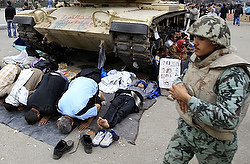 Men pray in front of a tank during a protest in Cairo Feb. 7. (CNS photo/Goran Tomasevic, Reuters)