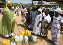 Cardinal Peter Turkson of Cape Coast, Ghana, blesses jugs of water to be used as holy water June 9 during his two-day pastoral visit to the small village of Ekumfi Nanaben.