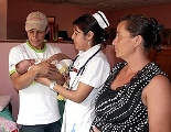 With his wife nearby, a man is handed their baby girl from a nurse in Nicaragua in early August. (CNS photo/Liz Quirin, The Messenger) (Sept. 26, 2011)