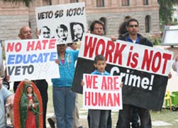 Immigration rights advocates hold up signs outside the the Arizona Capitol in Phoenix April 21 to oppose a bill that would make it a crime to be in the United States illegally. The bill, which the Legislature passed April 19, is waiting for a signature f rom Gov. Jan Brewer. (CNS photo/J.D. Long-Garcia, Catholic Sun)
