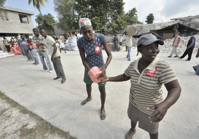Earthquake survivors in the Haitian city of Leogane unload emergency supplies provided by Caritas Internationalis and Diakonie, Jan. 20. (CNS /Paul Jeffrey)
