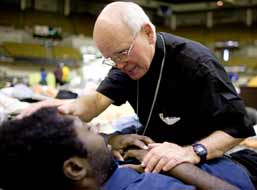 Archbishop Alfred C. Hughes blesses Hurricane Katrina evacuee Gerald Williams of New Orleans at a shelter in Baton Rouge, La., in this Sept. 11, 2005, photo. (CNS)