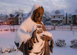 A snow-covered statue of the Sacred Heart of Jesus is seen at dusk on the grounds of Sacred Heart Cathedral in Rochester, N.Y. (CNS file photo)