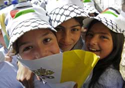 Palestinian girls smile next to a papal flag as Pope Benedict celebrates Mass in Bethlehem (CNS photo)
