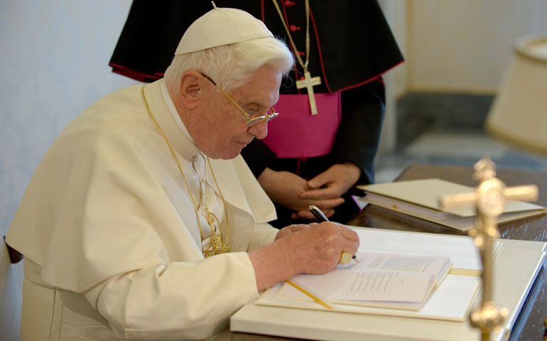 Pope Benedict XVI signs a copy of his encyclical Caritas in Veritate at the Vatican in July 2009. (CNS/Catholic Press Photo/L’Osservatore Romano)