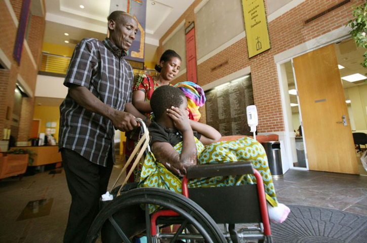 Cikoma Nsabimana, left, and his wife, Nyirategura Mukamurehe, wheel their daughter, Nyiramahirwe Mukamujeni, out of Catholic Charities in Houston. The family, which is from the Democratic Republic of Congo, resettled in Houston a year ago and has been able to become self-sufficient after being helped by the Catholic organization. (GSR/Nuri Vallbona)