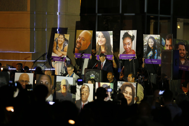 People hold photos of the mass shooting victims during a moment of silence at a vigil in San Bernardino, Calif., on Dec. 7, 2015. (Mike Blake/Reuters)