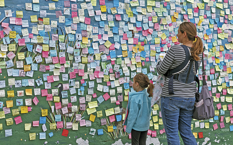 A woman and girl read sticky notes with messages of resilience, resistance and love on a wall in Oakland, Calif., Nov. 20. The notes were based on a phenomenon that began in New York City in response to the election of Donald Trump. (Newscom/Splash News/John Orvis)