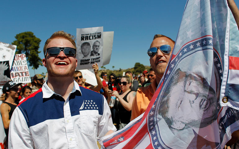 Supporters of Republican presidential candidate Donald Trump hold up a flag emblazoned with his picture as they stand amid anti-Trump demonstrators during a campaign rally in Fountain Hills, Ariz., March 19. (Newscom/Reuters/Ricardo Arduengo)