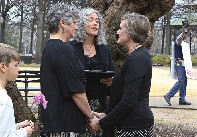 A protester waving a Bible walks past as two women named Donna and Tina get married in a park outside the Jefferson County Courthouse in Birmingham, Ala., on Feb. 9, 2015. (Reuters/Marvin Gentry)