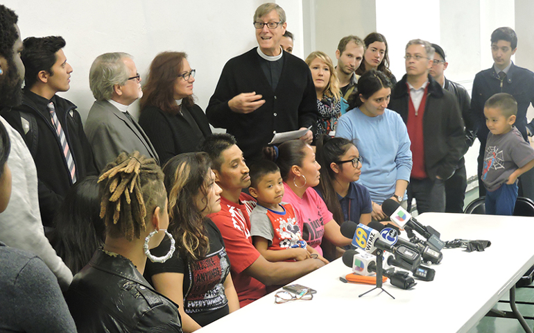 Supporters surround Javier Flores and his family during a press conference in the basement of Arch Street United Methodist Church in Philadelphia on Nov. 15, 2016. The group gathered to announce that Flores has taken asylum in the church. Senior pastor Robin Hynicka stands immediately behind him. (RNS photo by Elizabeth Evans)