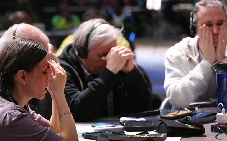 Delegates pause for a moment of prayer at the 2016 United Methodist General Conference. From left, Vasylyna Babych from the Ukraine-Moldava Provisional, and Alexander Pererva and Alexandr Meinikov from the Southern Russia Provisional. (Kathleen Barry, UMNS)