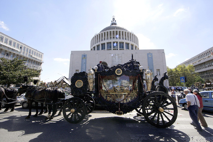 An ornate hearse pulled by six, black-plumed horses, carries the body of Vittorio Casamonicato by a Roman Catholic basilica in the Rome suburbs, where a funeral Mass was celebrated Aug. 20. Casamonica, 65, the head of a notorious Rome crime family, was given a lavish funeral on Thursday, with a helicopter dropping red rose petals on mourners and a brass band playing the theme tune from the “Godfather” movie. Picture taken August 20, 2015. (RNS/Stringer)