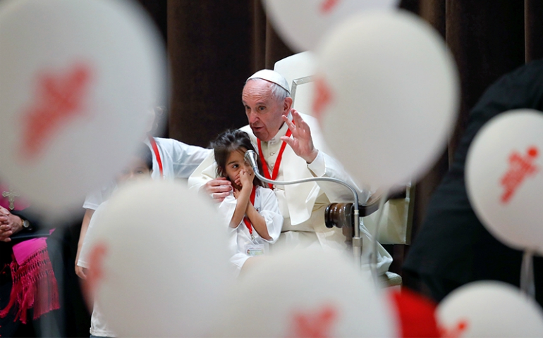 Pope Francis talks as he embraces a child during a special audience with members of the "Train of the children" at the Vatican, on June 3, 2017. (Courtesy of Reuters/Remo Casilli)