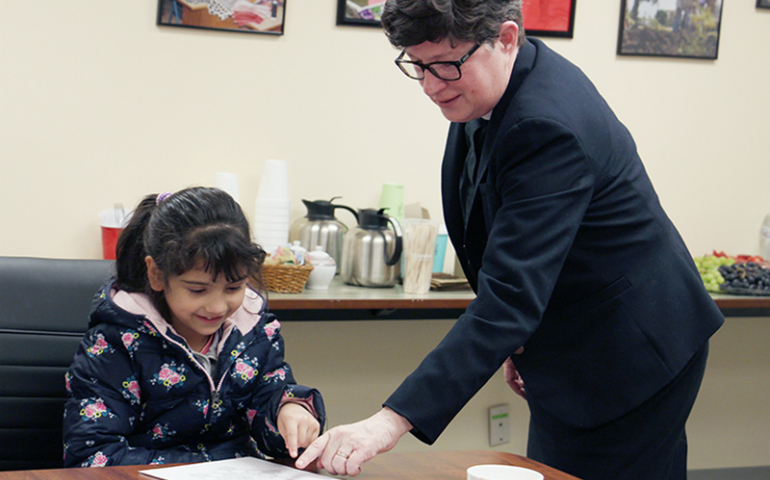 The Rev. Elizabeth Eaton, presiding bishop of the Evangelical Lutheran Church in America, talks with Dalal, a 6-year-old refugee from Syria, about her artwork March 21 at RefugeeOne in Chicago. (RNS/Emily McFarlan Miller)