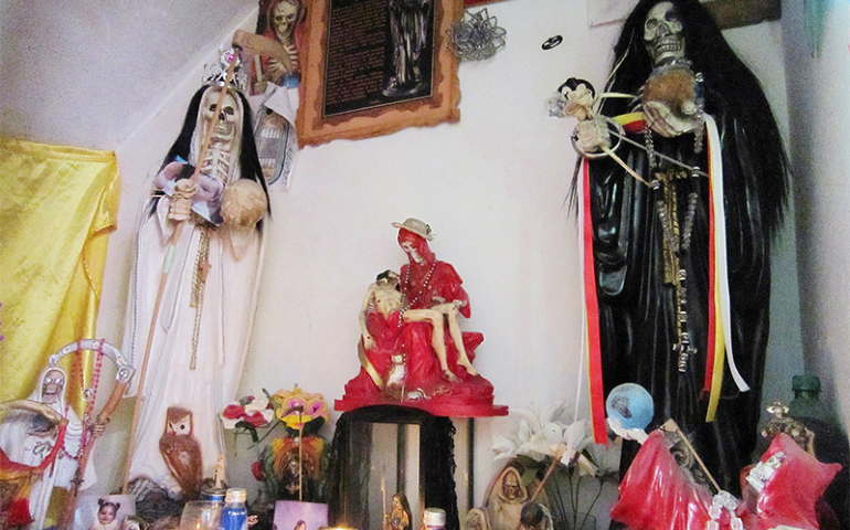 A shrine to Santa Muerte kept in the house of Betzy Ballesteros in Guadalajara, Mexico. The shrine includes statues, candles, candy and photos of several of Ballesteros’ transgender friends who were murdered and abandoned. (RNS/tephen Woodman)