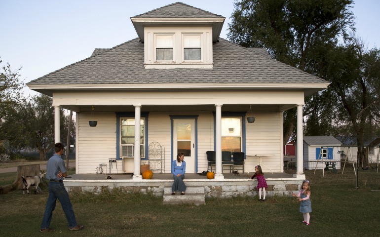 Mary Ford sits on her front porch as her husband, Kevin, and their children play together at sunset in 2013 on their family farm in St. Leo, Kan. Many family farmers in the United States are facing the worst combination of events since the "farm crisis" of the mid-1980s. (CNS photo/Tyler Orsburn)