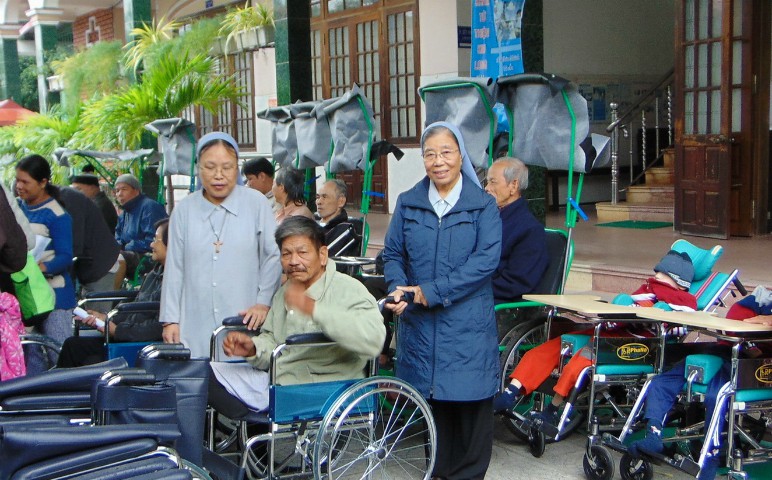 On June 25, Daughters of Mary Immaculate Sisters Cecilia Do Thi Lan, right, and Mary Vu Thi Ngoc offer wheelchairs to people who have lost the use of their limbs at Kim Long Charity Clinic in Hue. (GSR photo / Peter Nguyen)