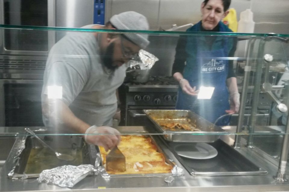 Chef Dwight Tiller cuts enchilada casserole during dinner at Bishop Sullivan Center's One City Café in Kansas City, Missouri, Feb. 26. He is assisted by volunteer Karen Stigers. (NCR photo/Maria Benevento)