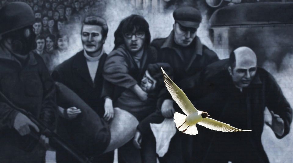 A seagull flies in front of a mural which shows a group of men, led by then-Fr. Edward Daly, right, carrying the body of shooting victim Jackie Duddy during 1972's Bloody Sunday in Londonderry, Northern Ireland.(CNS/Reuters/Cathal McNaughton) 