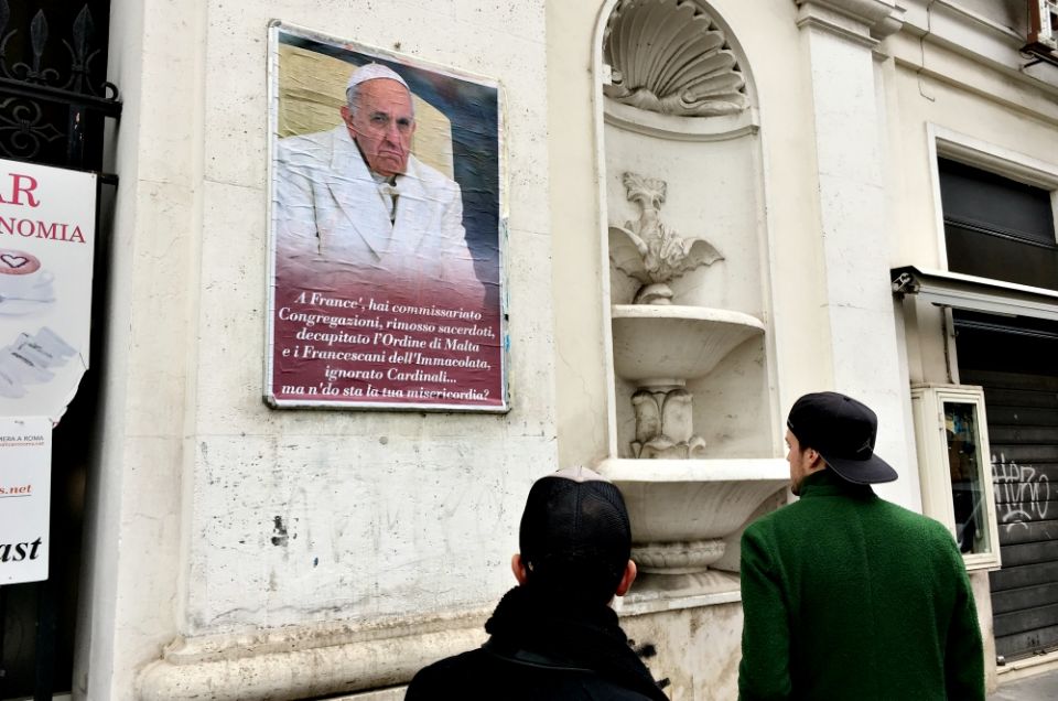 People look at a poster expressing criticism of Pope Francis in Rome Feb. 5, 2017. Numerous copies of the poster were placed in the center of Rome but were quickly covered or removed by city authorities. (CNS/Paul Haring) People look at a poster expressing criticism of Pope Francis in Rome Feb. 5, 2017. Numerous copies of the poster were placed in the center of Rome but were quickly covered or removed by city authorities. (CNS/Paul Haring)