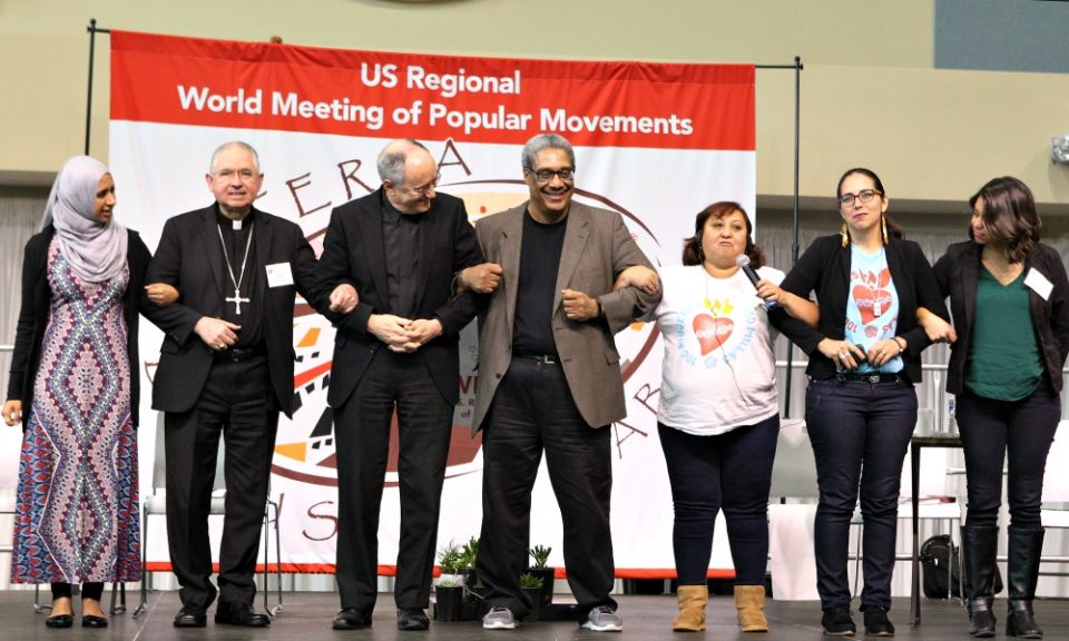 Los Angeles Archbishop José Gomez, second from left, links arms with other participants in a panel discussion on migration issues Feb. 17, 2017, during the U.S. Regional World Meeting of Popular Movements in Modesto, California. (CNS/Dennis Sadowski)