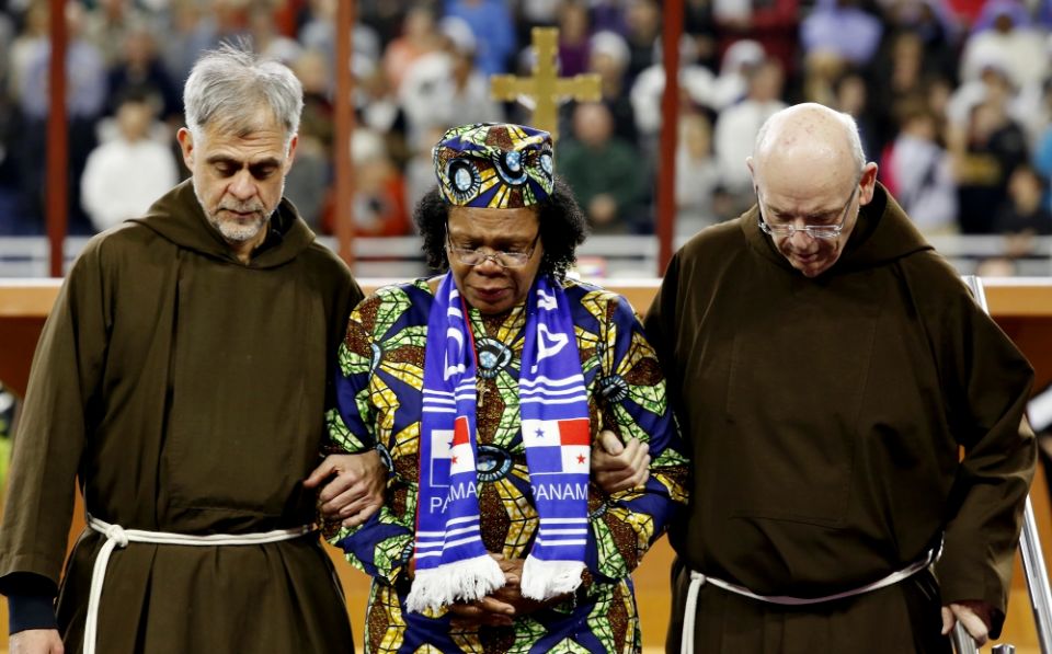 Paula Medina Zarate is escorted by two Franciscans as she carries a relic of Blessed Solanus Casey during his beatification Mass Nov. 18 at Ford Field in Detroit. (CNS/Courtesy of Michigan Catholic/Jeff Kowalsky)