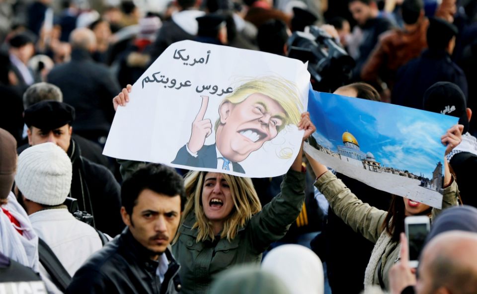 A protester near the U.S. embassy in Amman, Jordan, holds a lampoon of President Donald Trump Dec. 7. The cartoon reads, "America is the Arab leader." (CNS/Reuters/Mohamad Hamed) 