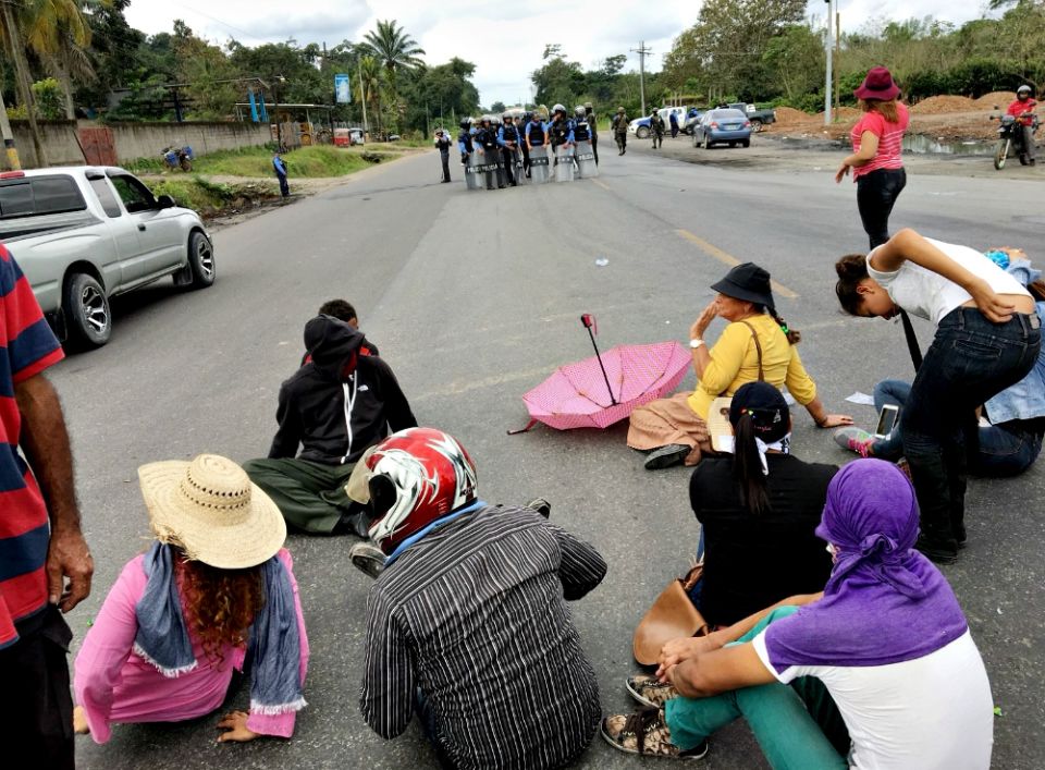 A circle of protesters on the highway forces traffic to pass on the shoulder as police face them nearby. (Tom Webb)