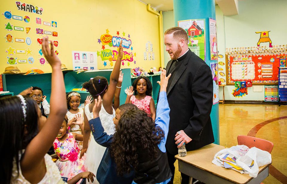 Fr. Matt O'Donnell, pastor of St. Columbanus Parish on Chicago's South Side, talks with kindergarten students at Augustus Tolton Catholic Academy before their graduation ceremony in 2017. (CNS/Courtesy of Natalie Battaglia)