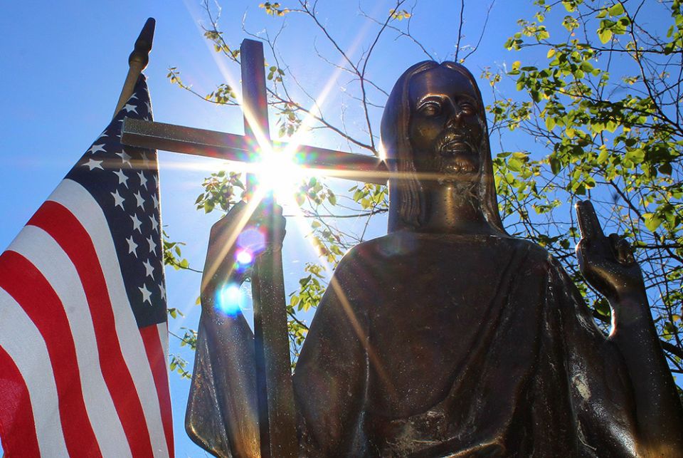 Sun shines through a statue of Christ on a grave marker alongside an American flag June 7, 2018, at St. Mary Catholic Cemetery in Appleton, Wisconsin. (CNS/Bradley Birkholz) Sun shines through a statue of Christ on a grave marker alongside an American flag June 7, 2018, at St. Mary Catholic Cemetery in Appleton, Wisconsin. (CNS/Bradley Birkholz)