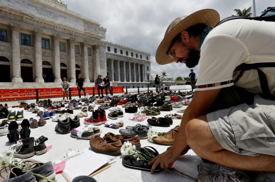A man in San Juan, Puerto Rico, places a pair of sandals in front of the capitol building June 1 to represent those killed by Hurricane Maria. (CNS/EPA/Thais Llorca)