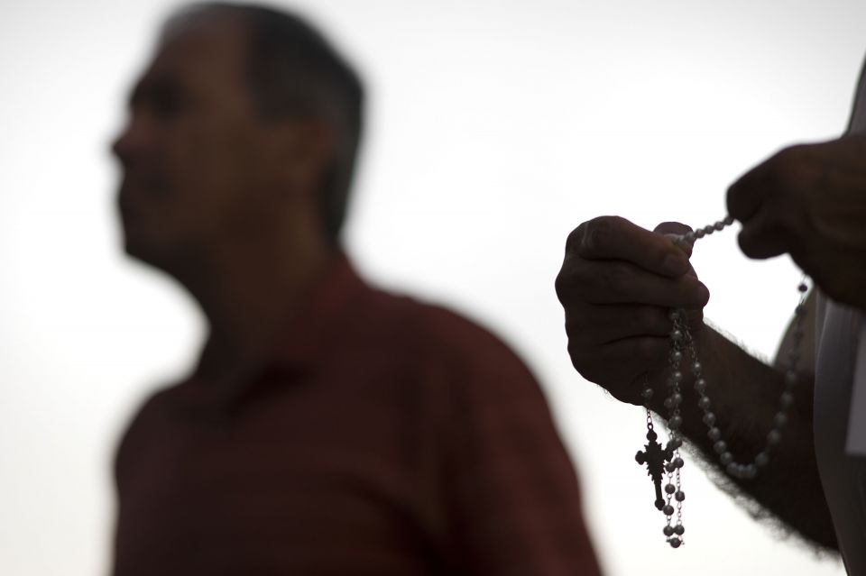 An attendee prays the rosary Oct. 1 during a public session on the issue of clergy sexual abuse at Our Mother of Confidence Parish Hall in San Diego. (CNS/David Maung)